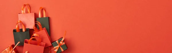 Top view of gift boxes and shopping bags on red background with copy space, panoramic shot — Stock Photo