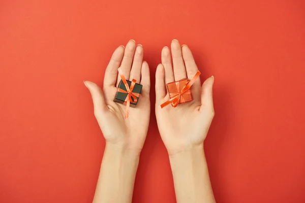 Vista parcial de la mujer sosteniendo pequeñas cajas de regalo sobre fondo rojo - foto de stock