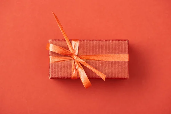 Vista superior da caixa de presente com arco e fita no fundo vermelho — Fotografia de Stock