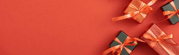 Draufsicht auf kleine Geschenkboxen auf rotem Hintergrund mit Kopierraum, Panoramaaufnahme — Stockfoto