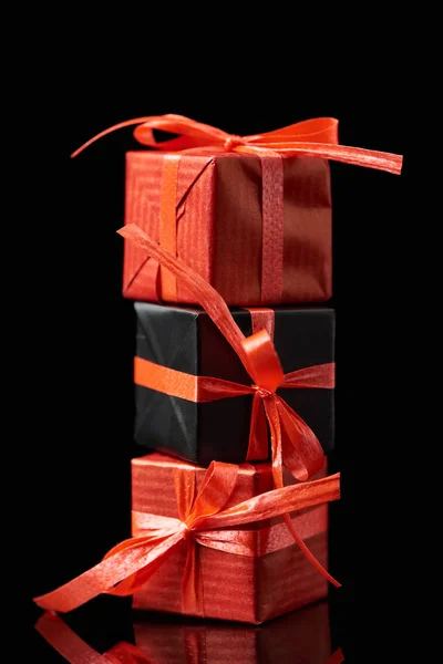 Regalos decorativos negros y rojos aislados en negro - foto de stock