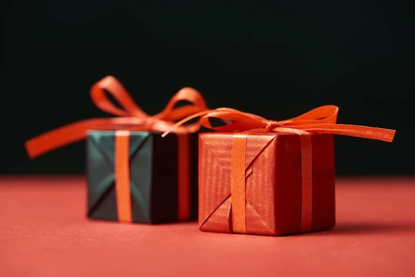 Selective focus of gift boxes with red ribbons isolated on black — Stock Photo