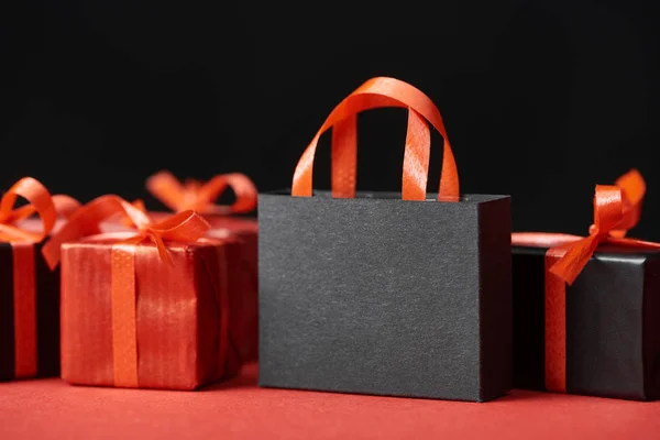 Red presents and shopping bag with copy space isolated on black — Stock Photo