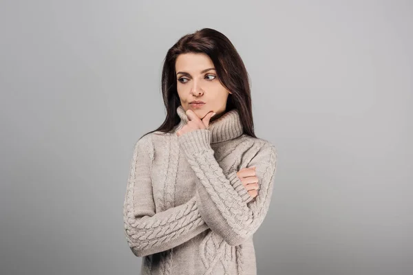 Задумчивая женщина в уютном свитере, изолированном от серого — стоковое фото