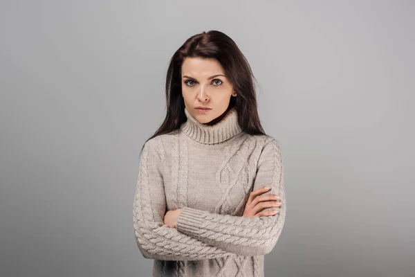 Upset woman standing with crossed arms isolated on grey — Stock Photo