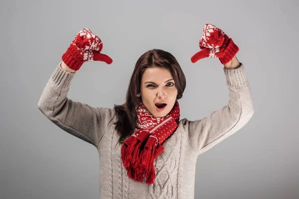 Незадоволена жінка в червоних рукавичках і шарфі показує великі пальці вниз ізольовані на сірому — стокове фото