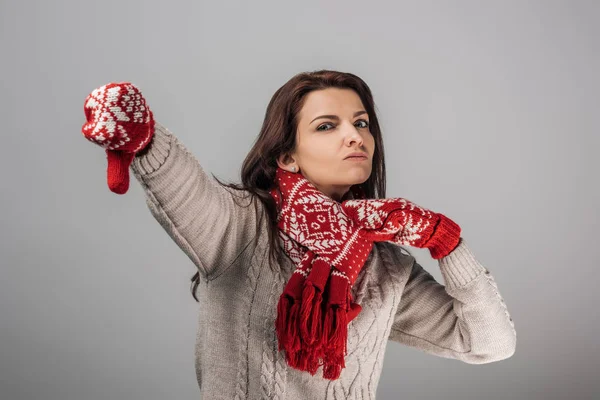 Незадоволена жінка в червоних рукавичках і шарфі з великим пальцем ізольований на сірих — стокове фото