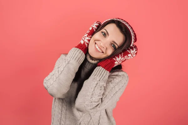 Femme positive en bonnet tricoté et gants couvrant les oreilles isolées sur rose — Photo de stock