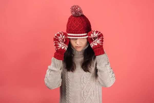 Donna in guanti rossi toccante cappello a maglia su rosa — Foto stock