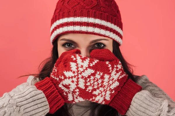 Donna in cappello a maglia che copre il viso con guanti rossi e caldi isolati su rosa — Foto stock