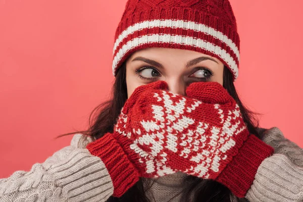 Woman in knitted hat covering face with red gloves isolated on pink — Stock Photo