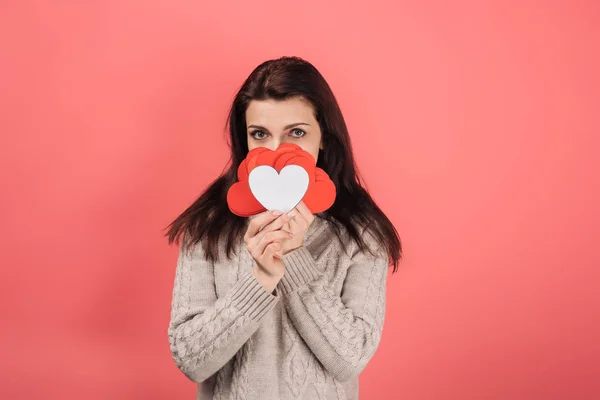 Woman in sweater covering face with heart-shaped paper artwork on pink — Stock Photo