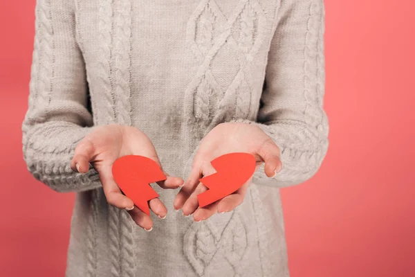 Vista recortada de la mujer sosteniendo obras de arte de papel con el corazón roto en rosa - foto de stock