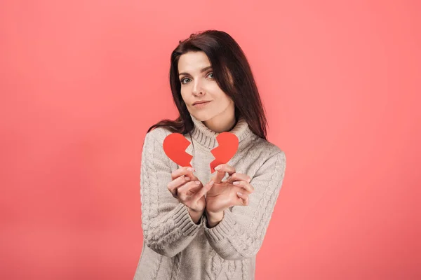 Mujer en suéter sosteniendo papel cortado con el corazón roto en rosa - foto de stock