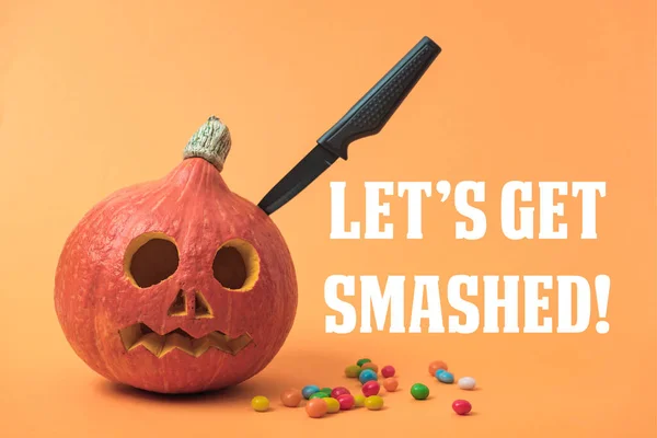 Gruseliger Halloween-Kürbis mit Messer und Bonbons auf orangefarbenem Hintergrund mit zerschmetterter Illustration — Stockfoto