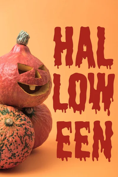 Gruselig geschnitzter Halloween-Kürbis auf orangefarbenem Hintergrund mit blutigem Halloween-Schriftzug — Stockfoto