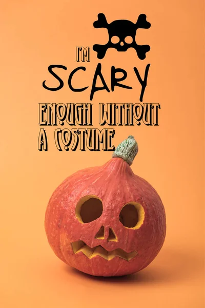 Spooky carved Halloween pumpkin on orange background with i am scary enough without a costume illustration — Stock Photo