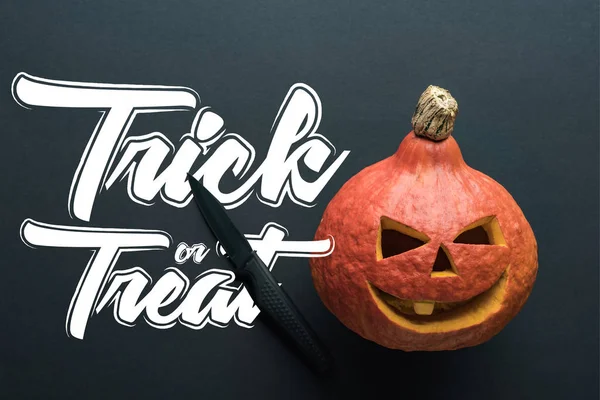 Vista superior de calabaza de Halloween espeluznante tallada con cuchillo sobre fondo negro con truco o ilustración tratar - foto de stock