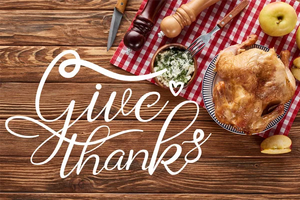 Vista superior de pavo asado y manzanas servidas en servilleta en mesa de madera con ilustración de agradecimiento - foto de stock