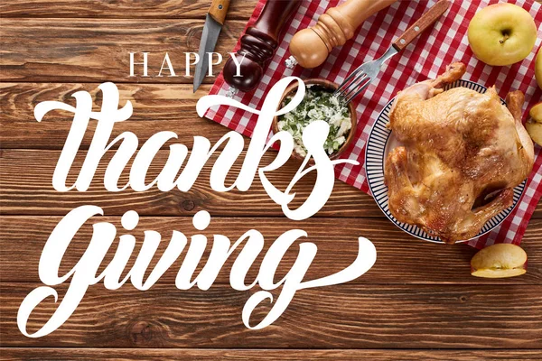 Top view of roasted turkey and apples served on napkin at wooden table with happy thanksgiving illustration — Stock Photo