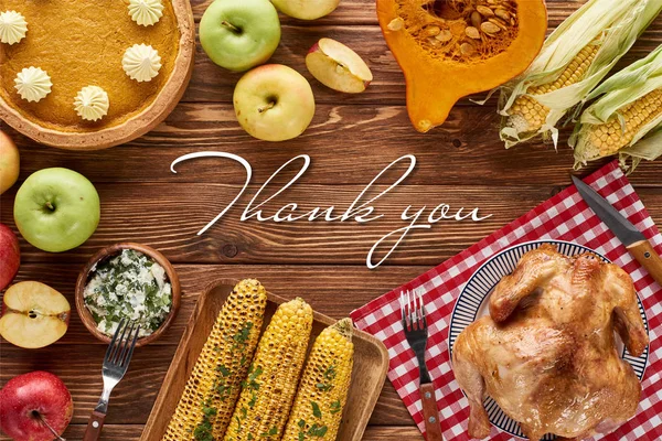 Draufsicht auf Kürbiskuchen, Truthahn und Gemüse, serviert am Holztisch mit Dankeschön-Illustration — Stockfoto
