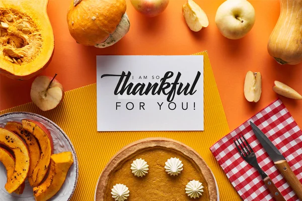 Vista dall'alto di torta di zucca, mele mature e scheda con io sono così grato per voi illustrazione su sfondo arancione — Foto stock