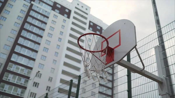 basketball ring in the courtyard of a multi-storey building. A new basketball ring with a net.