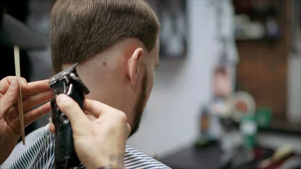 Mens haircut in barbershop. Master barber does a haircut to the client. Work with scissors and clipper. Close-up of the workflow