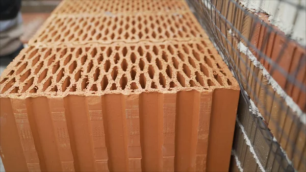 Red ceramic block for the construction of a private house.. A stack of red day bricks Brick with a rectangular round holes on a warehouse