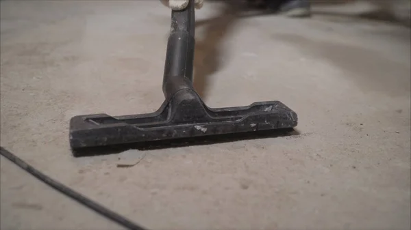 Worker vacuuming debris and dust from floor after drilling concrete wall. Worker vacuuming concrete floors