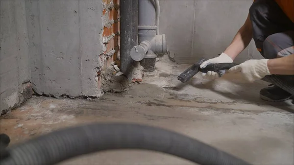 Worker vacuuming debris and dust from floor after drilling concrete wall. Worker vacuuming concrete floors