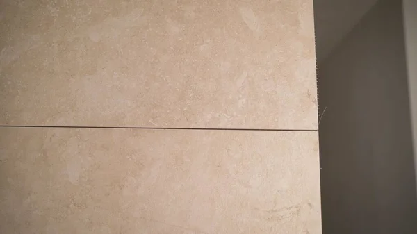 The process of grouting the joint between tiles in the bathroom. The master glues the tiles in the bathroom.. master tiler glues wall white ceramic tiles