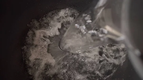 Close-up - water is poured into a construction bucket. Water is poured into a black bucket. Water is poured into a black plastic bucket