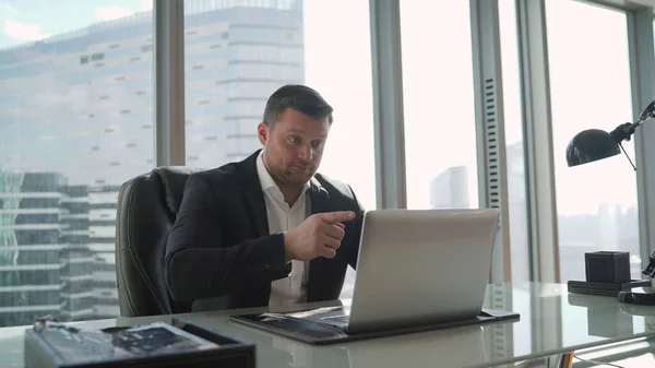 Angry businessman working at the computer from home. Stressful work environment concept. Businessman threatens while sitting at the laptop.