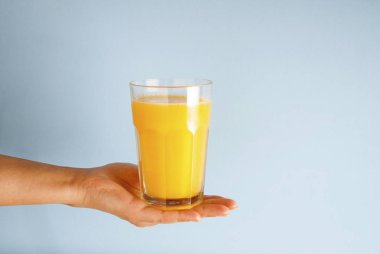 Bardak portakal suyu siyah saman mavi gemide izole tutan el