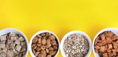 Kase mix tahıl müsli, kurutulmuş meyve, granola ve kopya alanı içeren satırı düzenlenen oatmeals. Sarı arka plan üzerinde izole. Üstten Görünüm. Afiş.