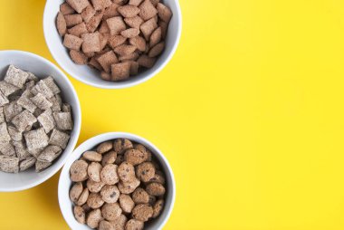 Kase tam tahıllı müsli, granola ve kopya alanı ile oatmeals. Sarı arka plan üzerinde izole. Üstten görünüm.