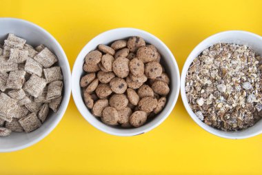 Kase tam tahıllı müsli, granola ve kopya alanı ile oatmeals. Sarı arka plan üzerinde izole. Üstten görünüm.