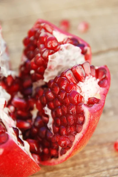 Broken pomegranate. Pomegranate grains. Pomegranate close up on wooden table.