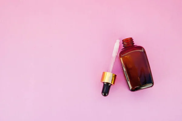 Beauty spa cosmetics, salon therapy concept. Glass cosmetic bottle on pink background.