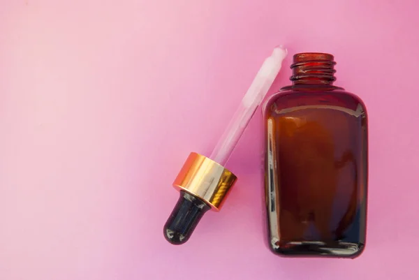 Beauty spa cosmetics, salon therapy concept. Glass cosmetic bottle on pink background.