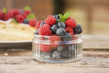 Küçük cam kase yaban mersini ve ahududu, yemek hazır dolu rustik tahtaya yerleştirilir.