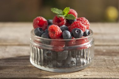 Küçük cam kase yaban mersini ve ahududu, yemek hazır dolu rustik tahtaya yerleştirilir.