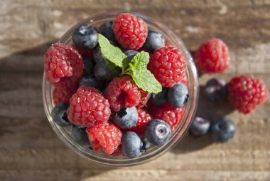 Küçük cam kase yaban mersini ve ahududu, yemek hazır dolu rustik tahtaya yerleştirilir.