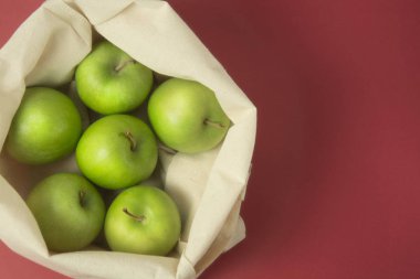 Biyo meyve - yeşil elma beyaz omuz çantası kumaş bez. Eko çanta, torba kırmızı arka plan alışveriş. Sıfır atık kavramı.