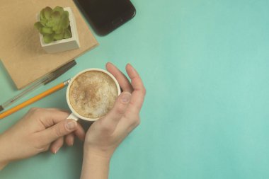El tutma kahve Kupası. Düz yatıyordu, en iyi görünümü office tablo Resepsiyon. Workspacewith smartphone, gadget, büro malzemeleri, kalem, kalem ve mavi zemin üzerine kahve fincanı.