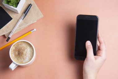 Holding, smarphone kullanarak kadının eller. iş yerinde, iş tablo witn kahve Kupası. Üstten Görünüm, kopya alanı.