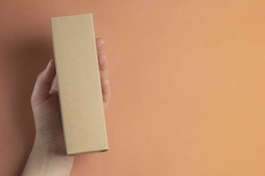 Boks, paketleme, teslimat kavramı. El tutma kutusu used üzerinde kahverengi veya mercan renkli arka plan uyarmak. Kopya alanı.