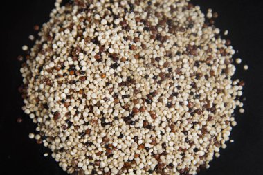 Yığın ham quinoa tahıl, üzerinde siyah arka plan üzerine karışık. Sağlıklı ve gluten free gıda. Uzay kopyalayın. Sağlıklı, temiz beslenme.
