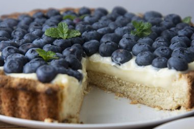 Böğürtlenli turta ya da kek krem ve çilek. Taze tatlı tatlı meyve ile. ev yapımı yiyecek, ahşap masa.